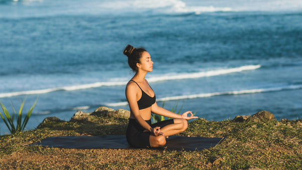 Frau macht Yoga am Wasser